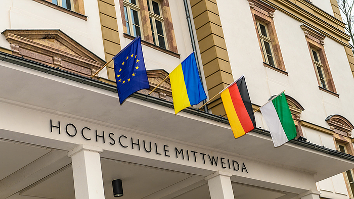 Four flags above the entrance portal of the main building of Mittweida University: Europe, Ukraine, Germany and Saxony.