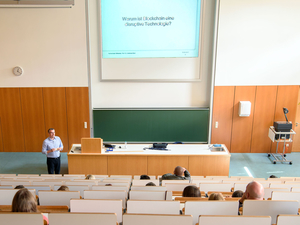 Prof. Dr.-Ing. Andreas Ittner steht neben einem Vorlesungspult in einem großen Hörsaal der Hochschule Mittweida, im Hintergrund ist eine unbeschriebene Tafel sichtbar.
