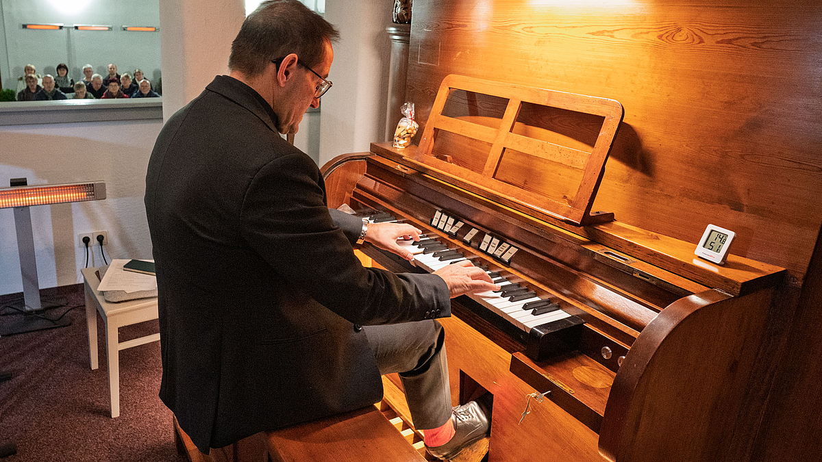 Männliche Person am einmanualigen Spieltisch einer Orger