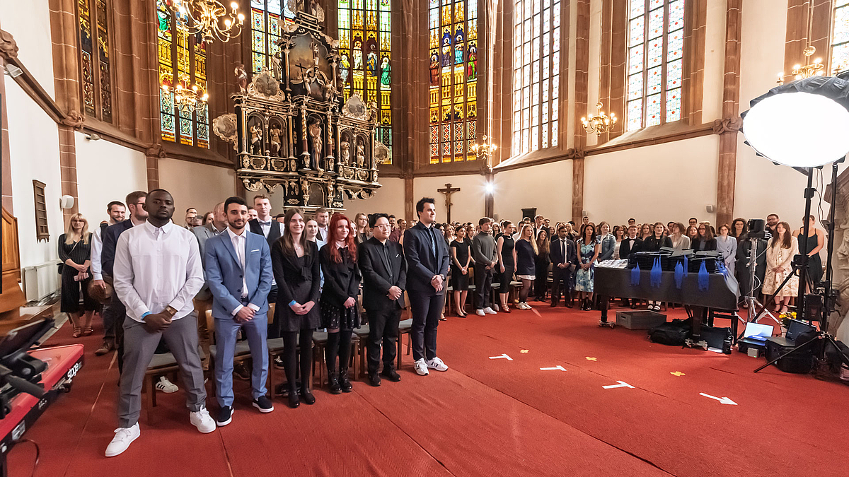 Absolvent:innen stehen im Altarraum.