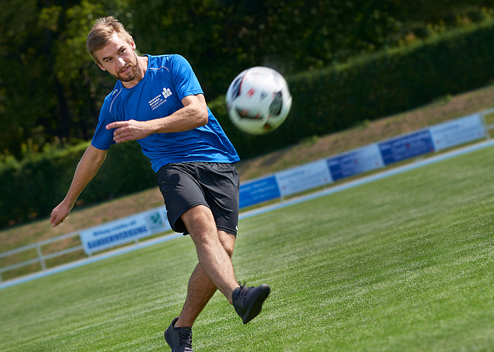 Ein Fußballer im Trikot der Hochschule Mittweida schießt einen Ball.