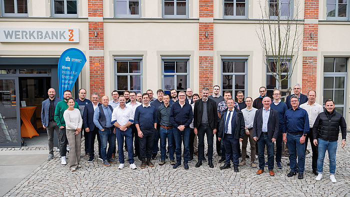 Gruppenfoto mit 32 Personen, darunter eine weibliche, vor einem Backsteingebäude mit der Aufschrift "Werkbank 32"