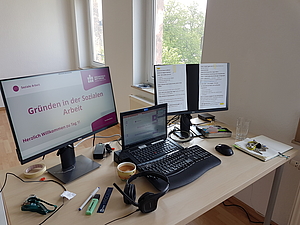 Blocktage in der Sozialen Arbeitgut strukturiert gestalten. Bild zeigt drei Bildschirme der Dozentin für das Seminar Gründen in der Sozialen Arbeit. Dazu Untensiliene wie Sprechgarnitur, Kaffeetasse und Textmarker.