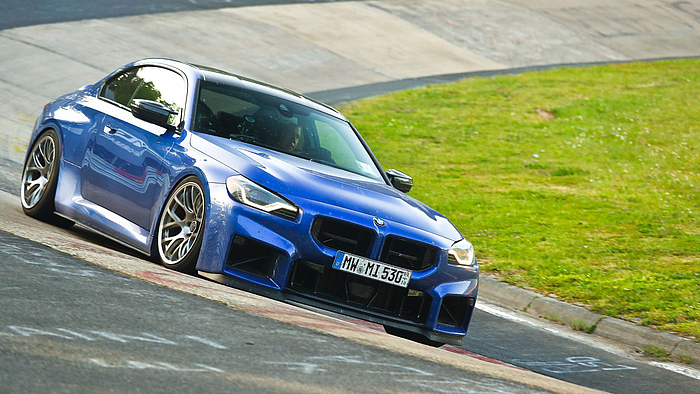 Ein blaues BMW Coupé in der Kurve einer Rennstrecke.