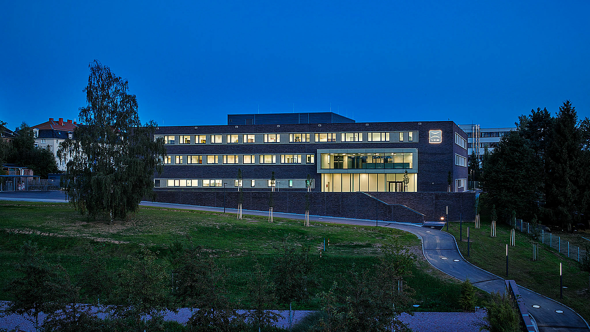 Das Foto zeigt dend Horst-Exner-Bau aus Richtung Norden/Zentrum für Medien und Soziale Arbeit am Abend vor nachblauem Himmel. Aus den zahlreichen Fenstern scheint Licht.