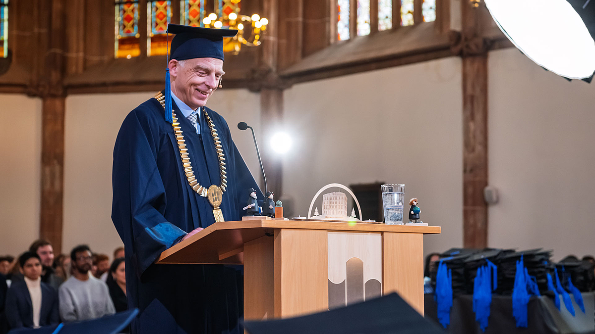 Diesselbe Person wie im Bild zuvor lächelnd am Rednerpult