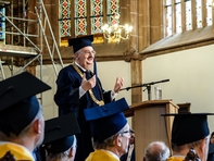 Rektor Ludwig Hilmer - stolz auf Absolventinnen und Absolventen im Rücken.