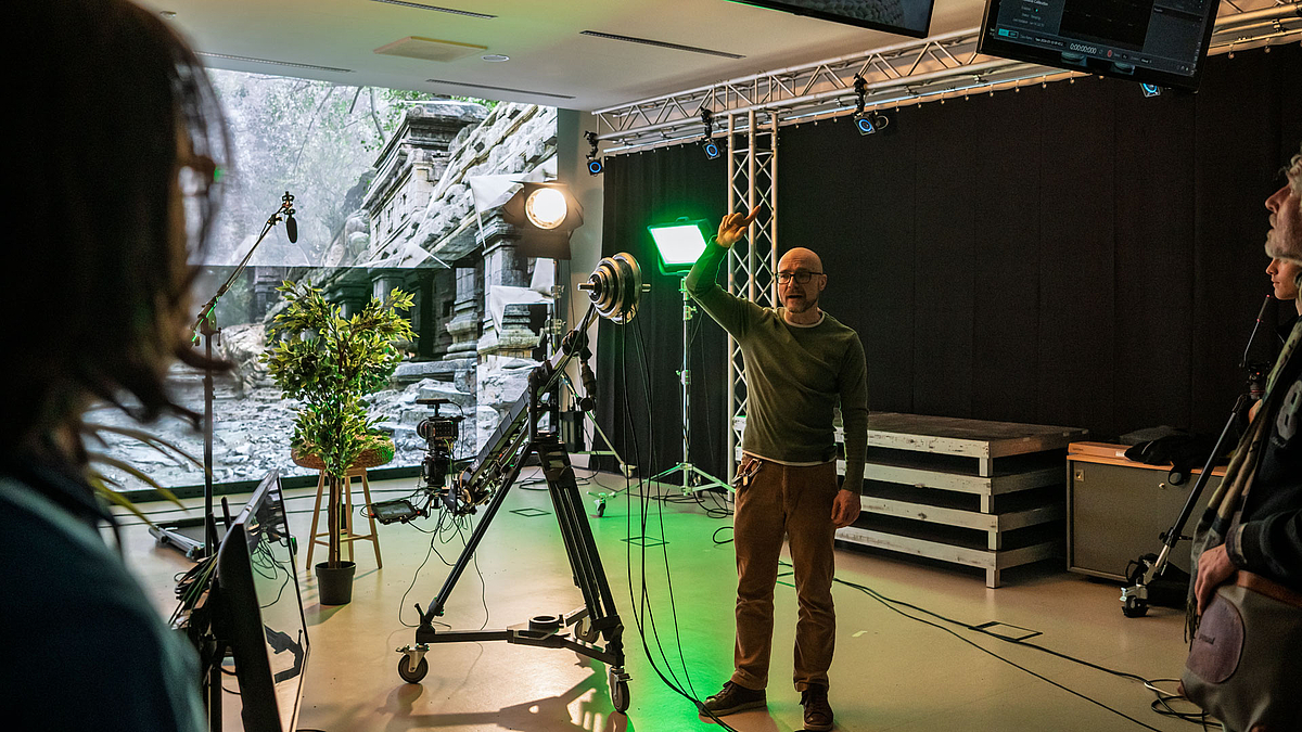 Virtual-Production-Studio Blick auf eine große LED-Wand im Hintergrund, davor Kameratechnik und eine männliche Person.