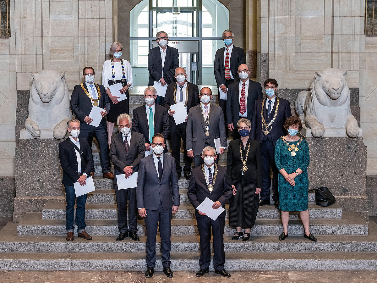 Das Foto zeigt auf den Stufen der von zwei Löwenstatuen eingerahmten Portaltreppe die Rektorinnen und Rektoren der 14 Hochschulen sowie die Dekane der beiden medizinsichen Fakultäten in Leipzig und Dresden mit dem Staatsmiminister der Mitte. Alle tragen FFP-Masken.