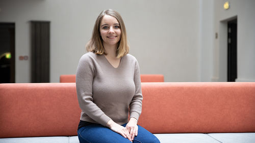 Alexandra Dutsch sitzt auf einem Sofa im Lichthof der Hochschule Mittweida und schaut in die Kamera.