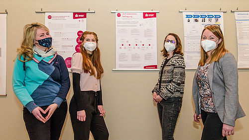 Das Foto zeigt vier Studentinnen Patricia, Rosa Clara, Friederike und Juliane vor einer Wand mit Forschungspostern. 
