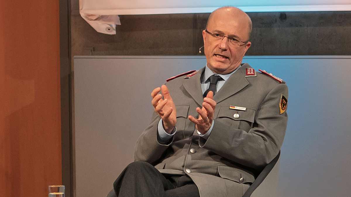 Männliche Person in Uniform spricht und gestikuliert.