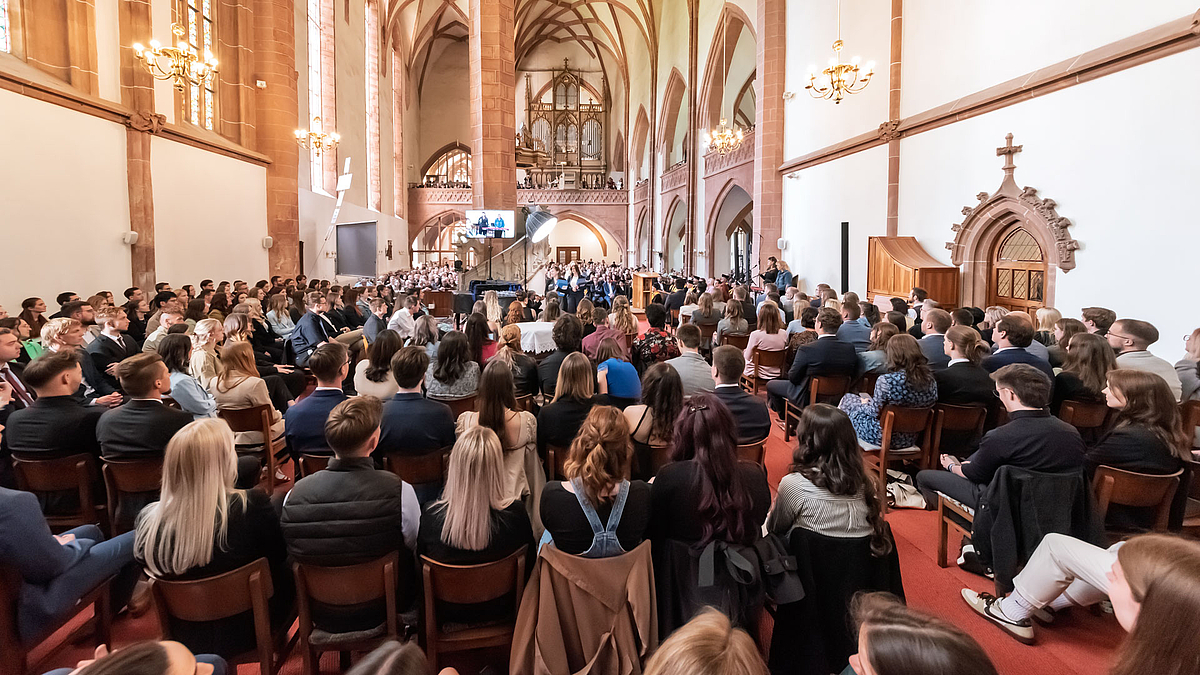 Blick aus dem Altarraum über Köpfe hinweg im das Kirchenschiff.