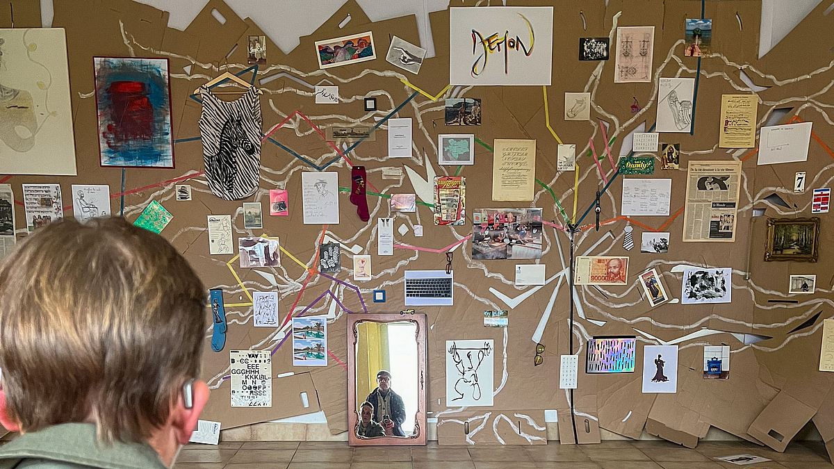 Eine Wand mit verschiedensten Elementen, meistens Gedrucktes wie an den verzweigten Ästen eines Baume hängend angeordnet.