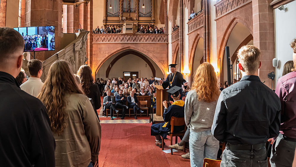 Blick aus dem Altarraum ins Kirchenschiff. Viele junge Menschen stehen.