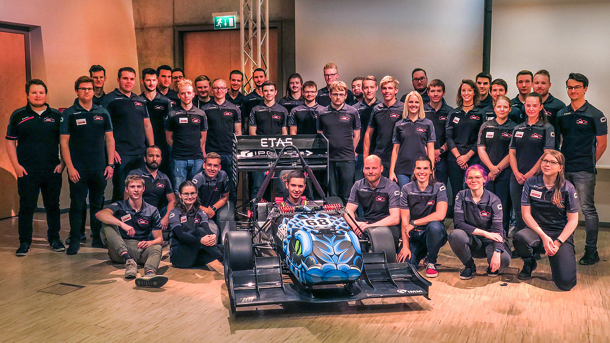 Das Team-Foto zeigt wiederum Mika Schuster im Auto sitzend, neben und hinter dem Auto stehend aber rund 40 jungen Menschen in einheitlichen Poloshirts.