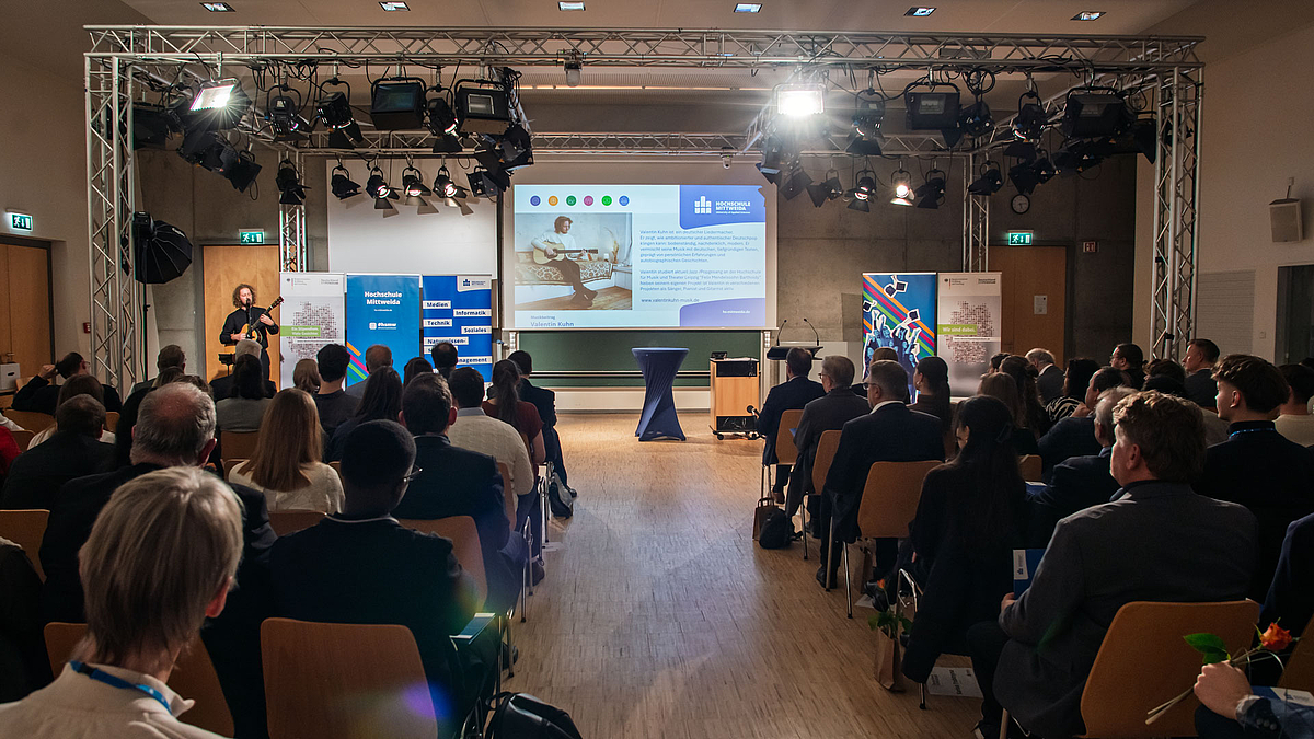 Blick über das Publikum hinweg auf einen Musiker mit Gitarre.