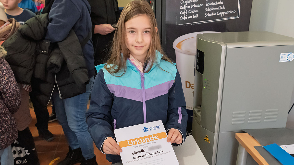 Mädchen hält ihre Urkunde in die Kamera und lächelt.