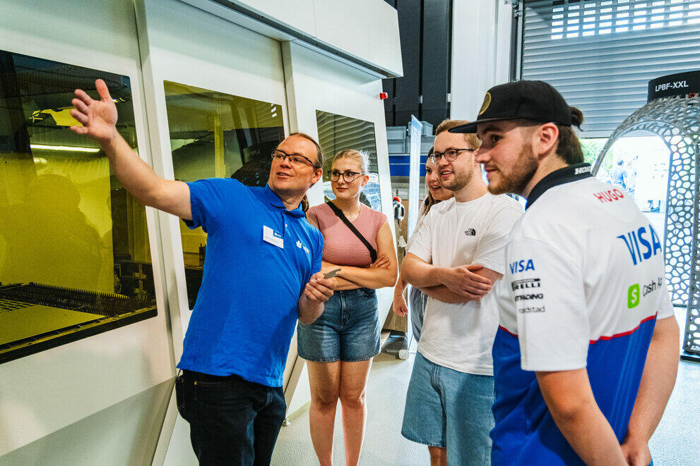 Guests are standing in front of a piece of equipment in the Laser Institute’s laboratory. A member of staff is explaining something.