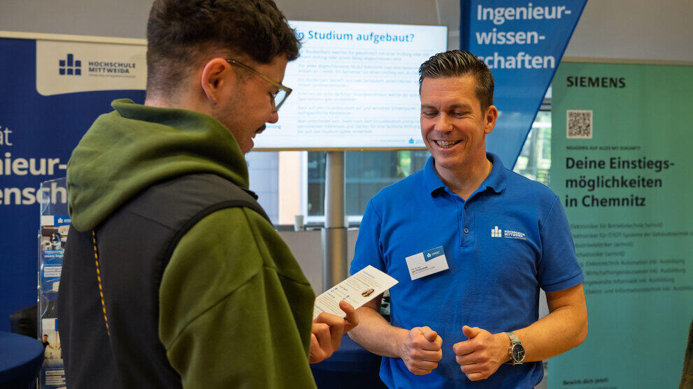 Men chatting in front of the ‘Engineering Sciences’ roll-up banner.