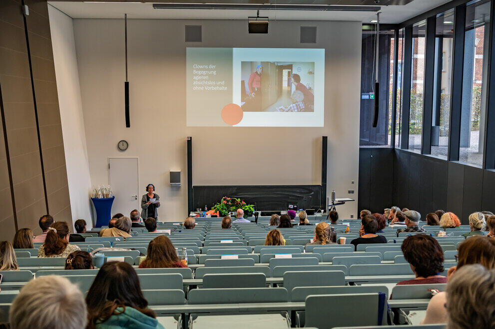 Personen sitzen im Hörsaal vor Referentin