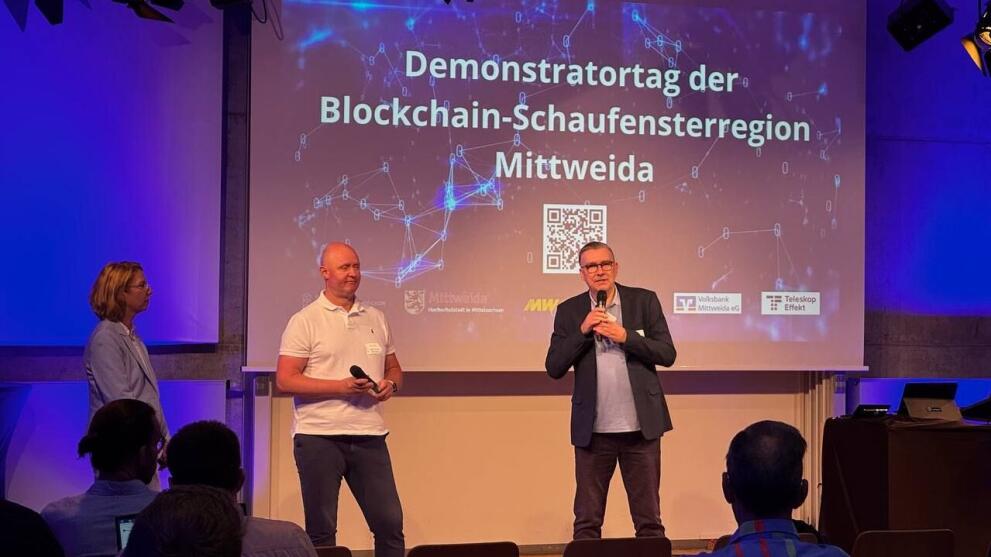 Drei Personen stehen vor einer Projektionswand