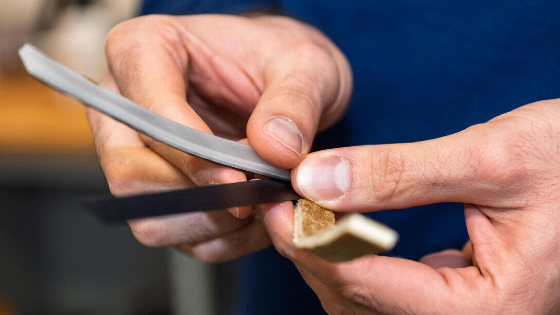 Naheinstellung auf die Werkstoffproben in den Händen. Die zwei Schichten sind zu erkennen.