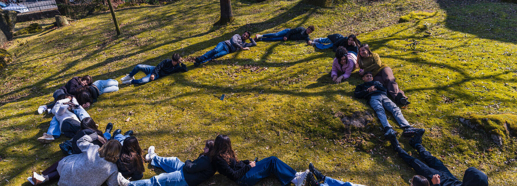 Jugendliche formen auf einer Wiese liegend ein Herz