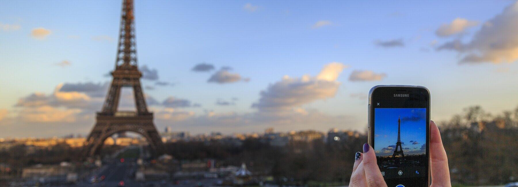 Hände machen mit Handy ein Foto vom Eifelturm
