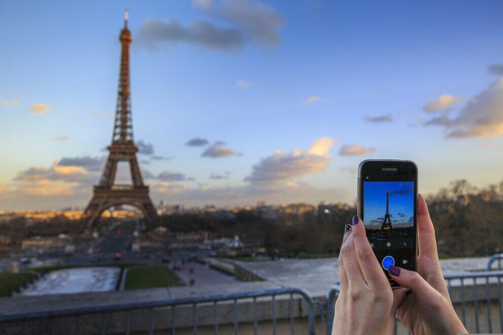 Hände machen mit Handy ein Foto vom Eifelturm