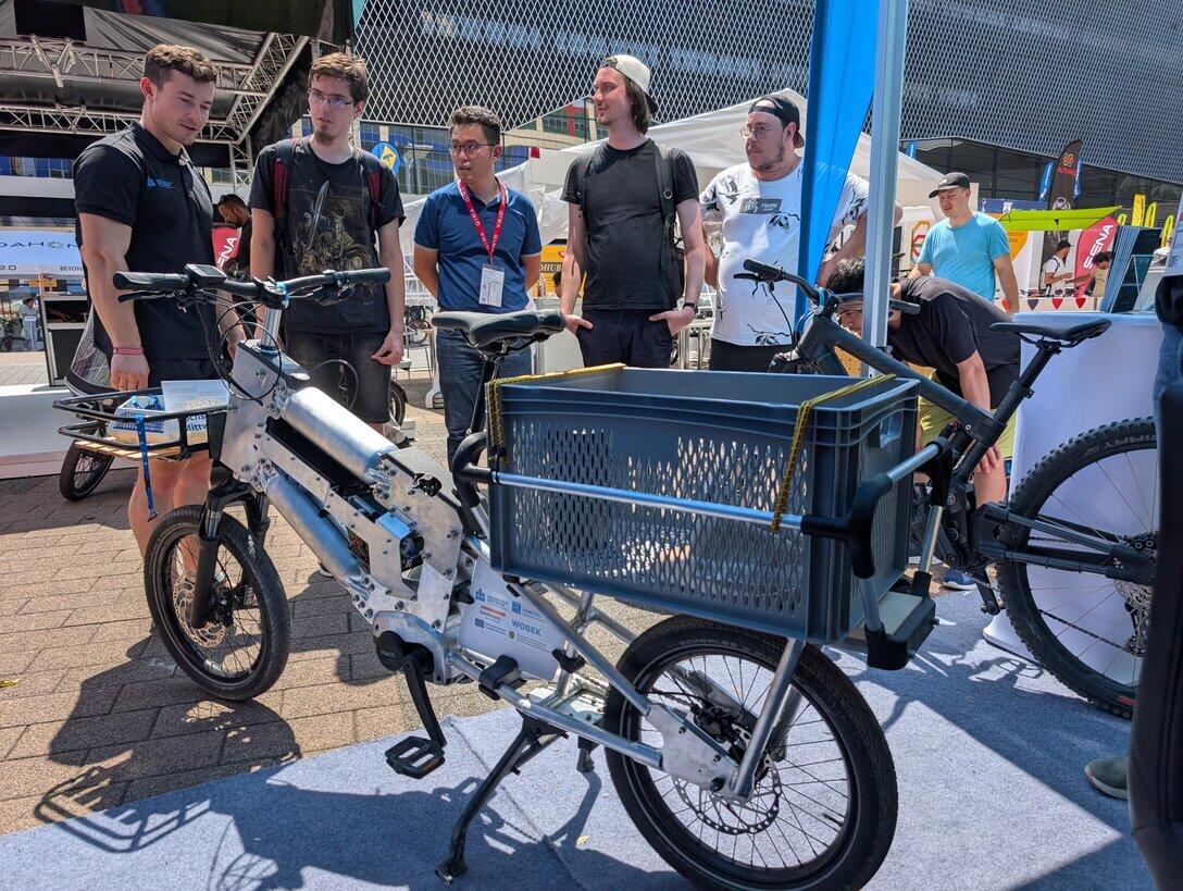 Personen setehen diskutierend hinter einem Lastenrad