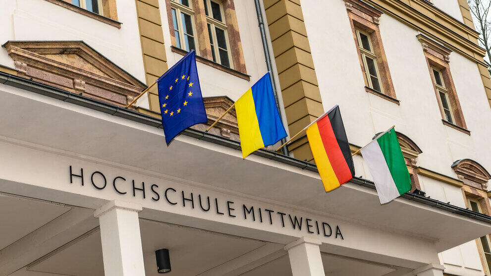 Vier Flaggen über dem Eingansgportal des Hauoptgbäudes der Hochschule Mittweida: Europa, Ukraine, Deutschland und Sachsen.
