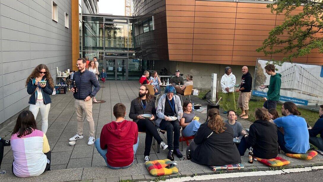 Personen sitzen auf Treppen vor einem Gebäude