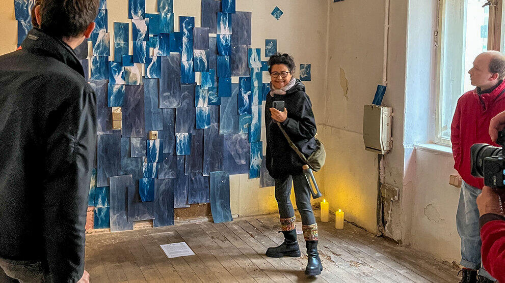 Cyanotypie-Abzüge von Gaze-Gewebe klettern die Wand in einem leerstehenden Laden empor – wie Rankpflanzen oder ein Ausschlag, der sich ausbreitet.