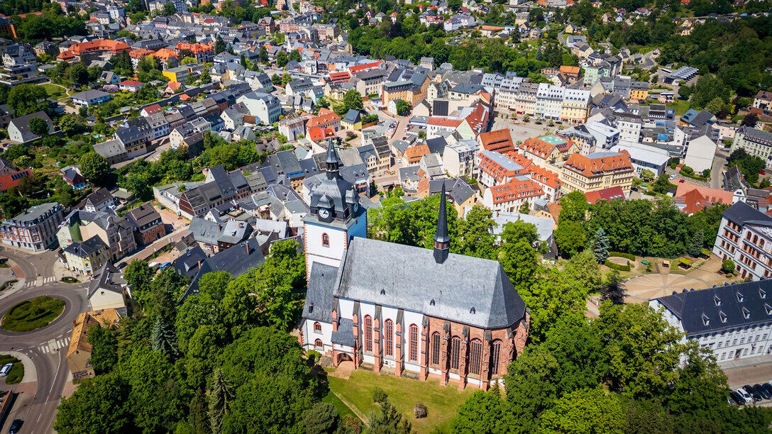 Lufaufnahme einer Kirche auf einem Berg, umgeben von einer Kleinstadt.