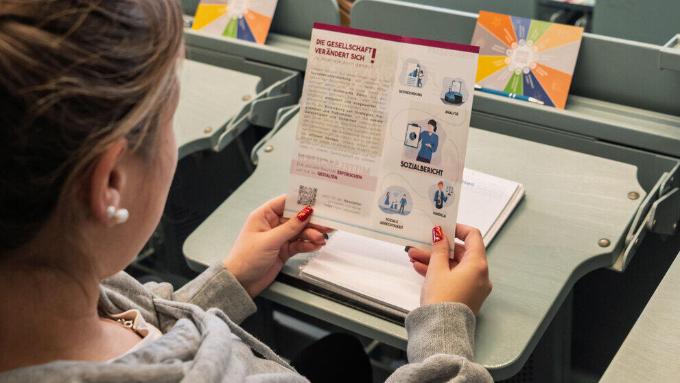 A person seen from behind, looking at a leaflet with the headline ‘Society is changing’.