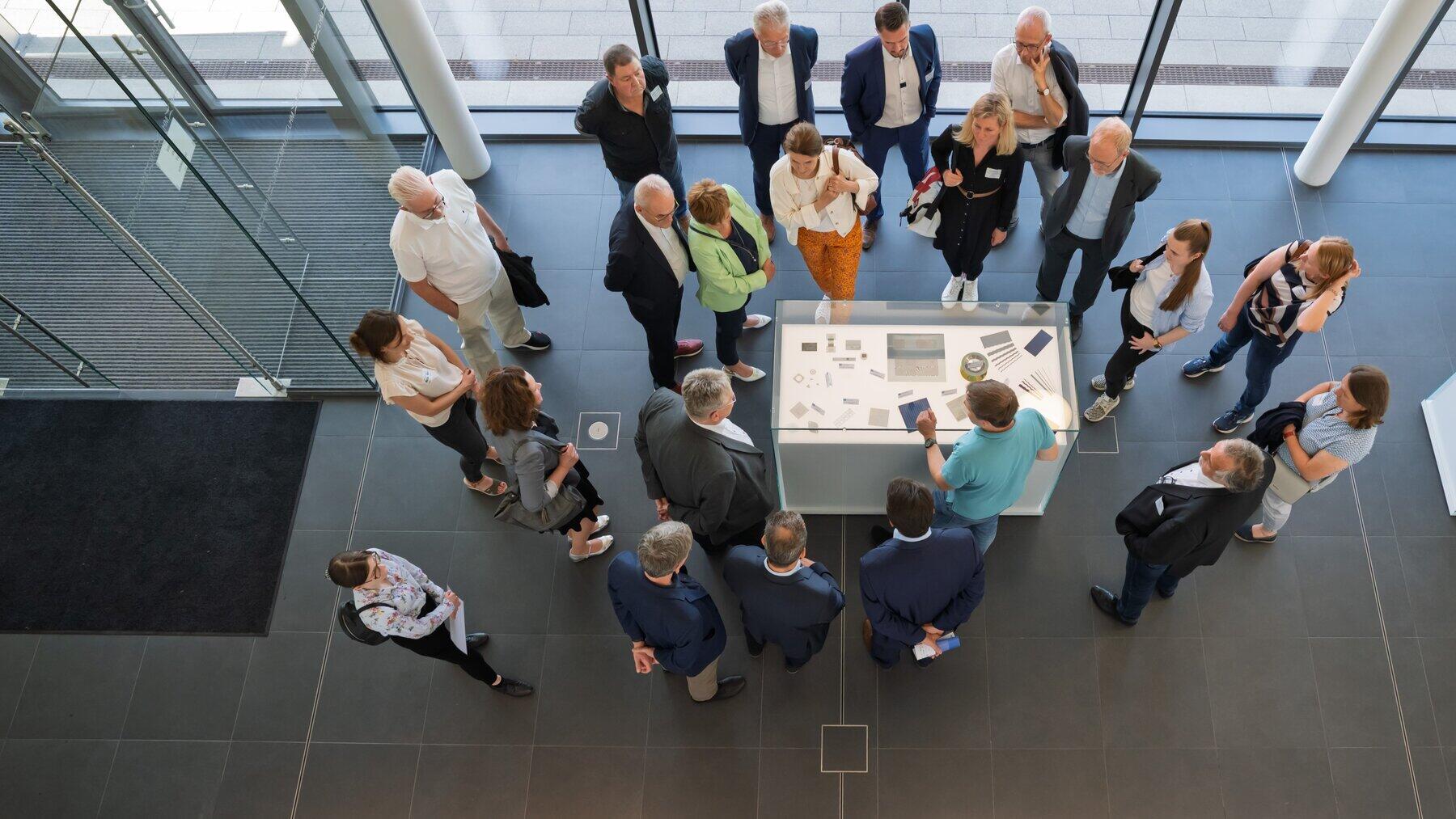 Blick von oben auf eine Personengruppe an einer Vitrine