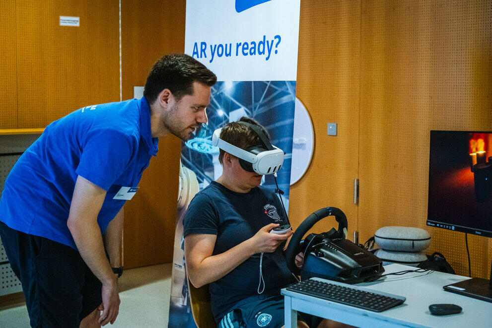 A visitor is trying out a pair of VR glasses under the guidance of a university staff member.