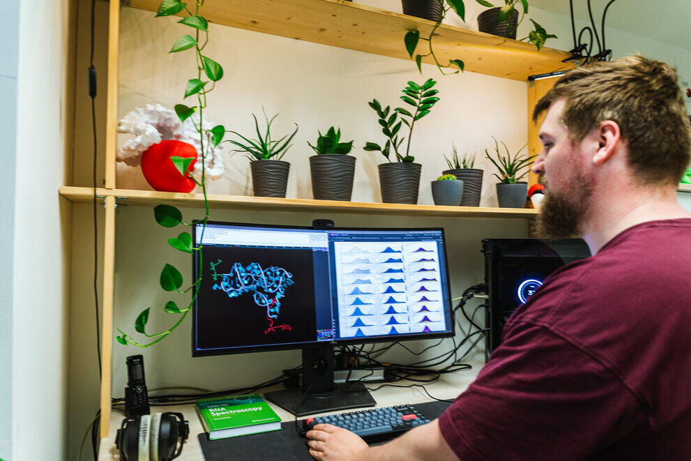 Ein Mann sitzt vor zwei Monitoren die eine Analyse von Einzelmoleküldaten für die 3D-Strukturmodellierung zeigt.