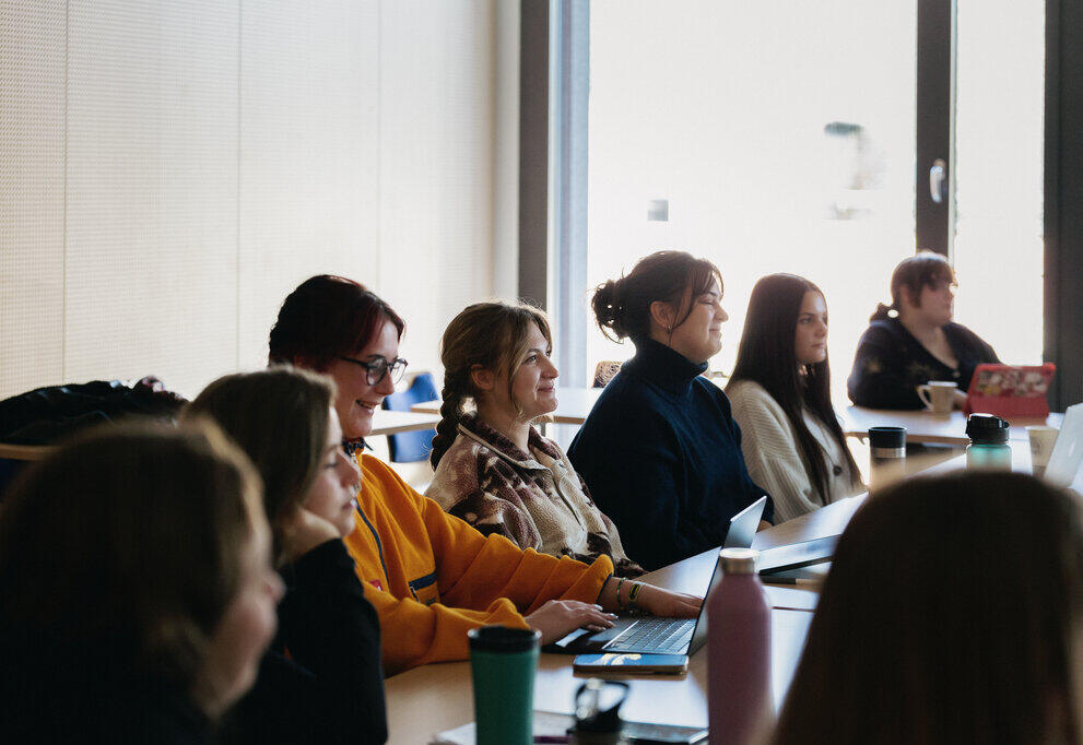 Many students sit in a lecture theatre listening to a lecture.