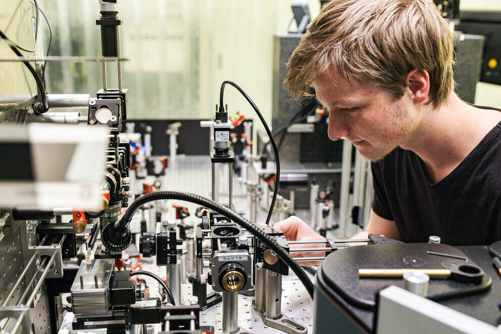 Ein wissenschaftlicher Mitarbeiter justiert einen Laserstrahlengang.