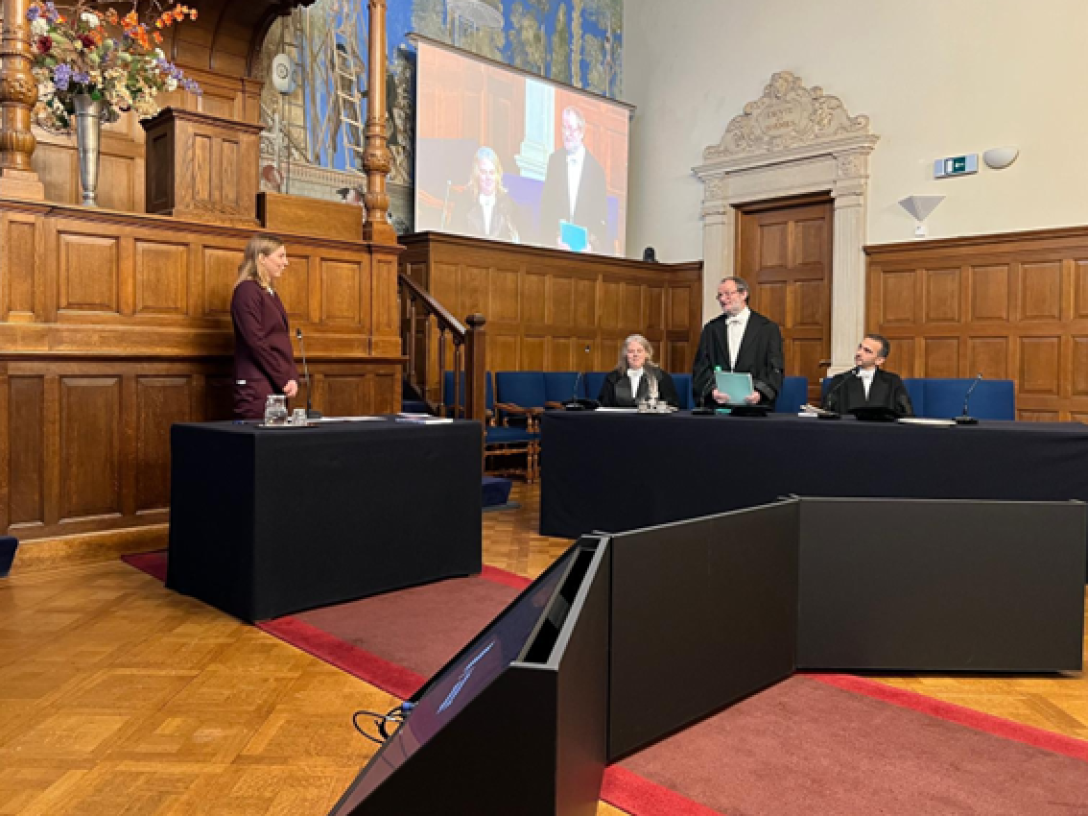 Blick in einen holzgetäfelten Saal mit einer Prüfungskommission und einer Promovendin