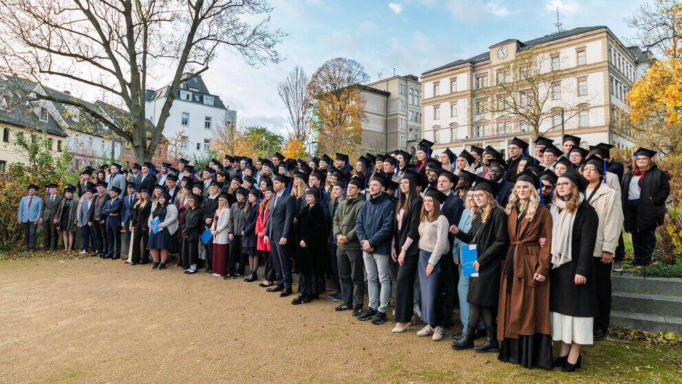 The graduates have gathered on the square below the main building for the group photo.