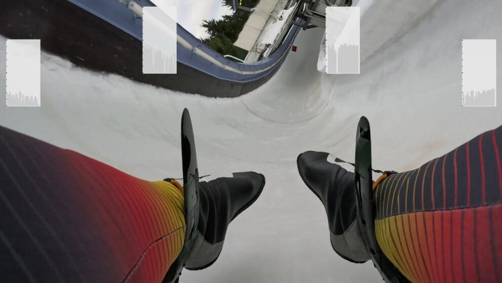 Blick auf die Füße eines Bobpiloten mit der Eisbahn und Fenstern für Messkurven