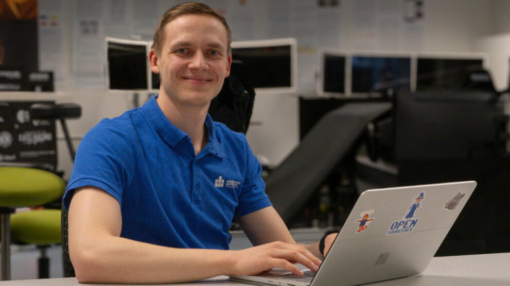 A man is sitting at his laptop, smiling