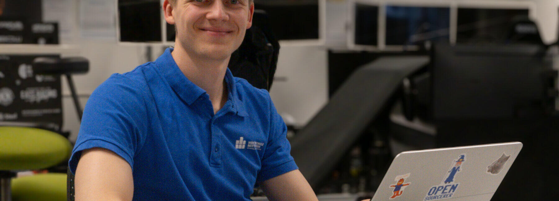 A man is sitting at his laptop, smiling