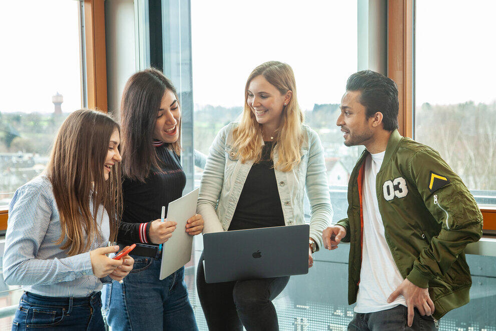 Studierende mit Laptop vor einer Fensterfront