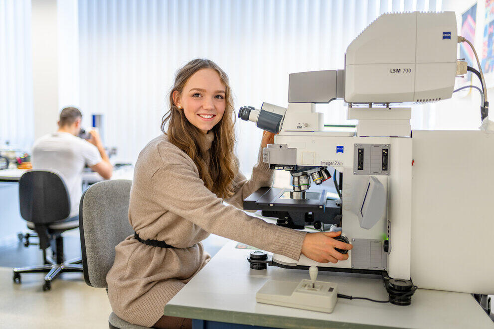 Eine Studentin stellt ein Lasermikroskop ein.