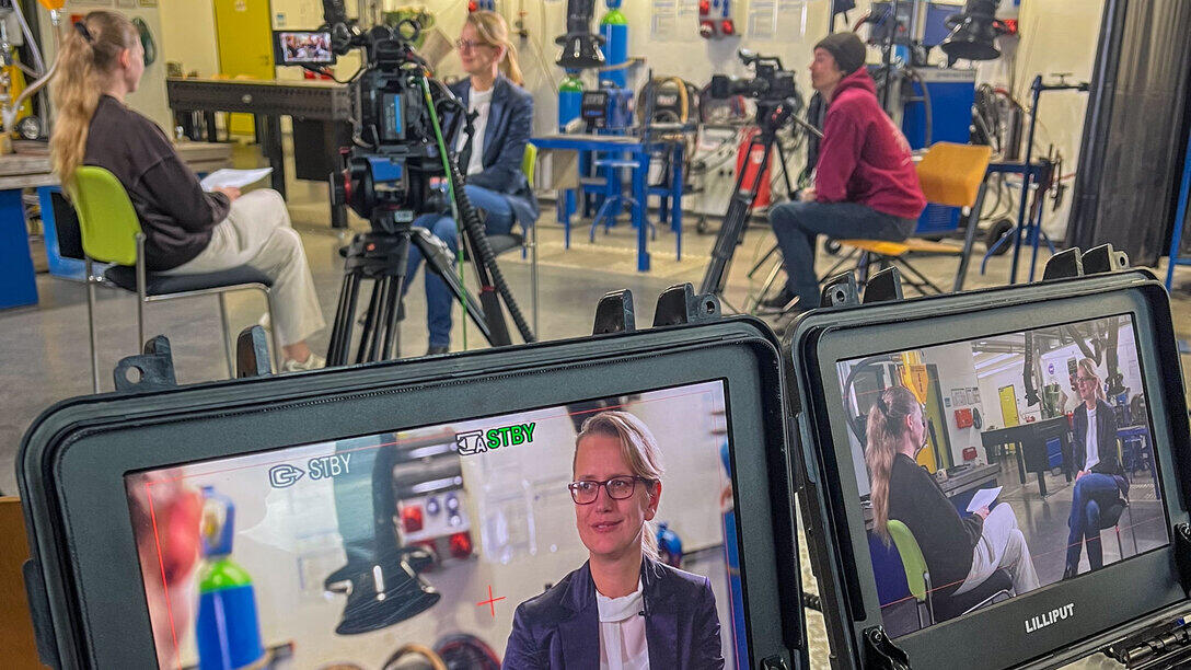 Blick über kleine Kontrollmonitore hinweg auf ein Interviewsetting mit mehreren Kameras