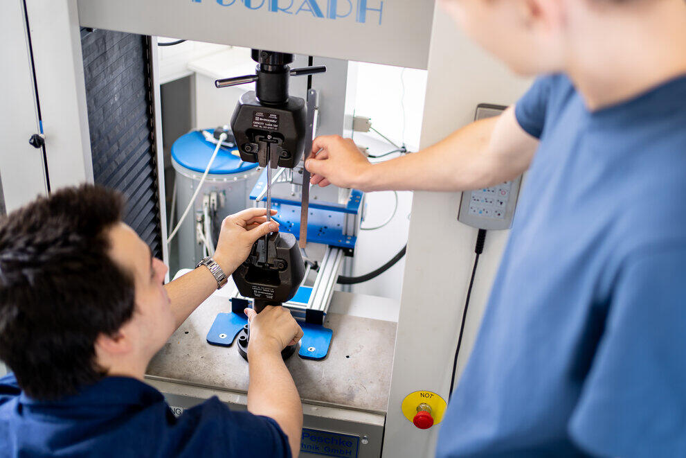 Two students are examining a universal testing machine.